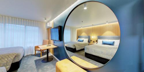 a hotel room with two beds and a mirror at Distinction Whangarei Hotel & Conference Centre in Whangarei
