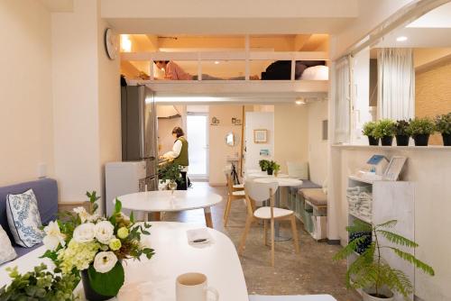 a room with tables and chairs and a person in a room at Casa Blanca Guesthouse in Nagasaki