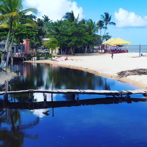 a beach with palm trees and a beach with blue water at Casa com piscina - Prado in Prado