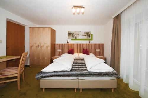 a bedroom with a bed and a table and a desk at Pension Pitze in Sölden