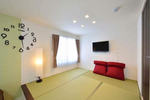 ein Wohnzimmer mit einer Uhr und zwei roten Stühlen in der Unterkunft Guest House Gifuhashima COCONE / Vacation STAY 33938 in Hashima