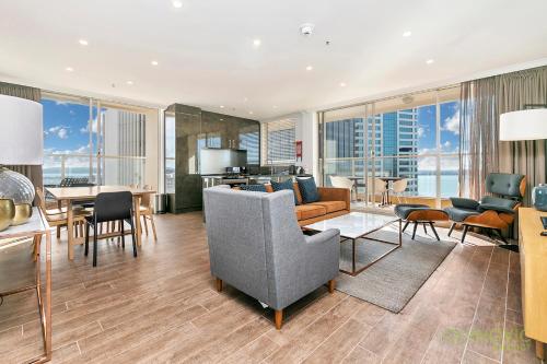 a living room with a couch and a table and chairs at QV Stays Heart of City with Stunning Views in Auckland