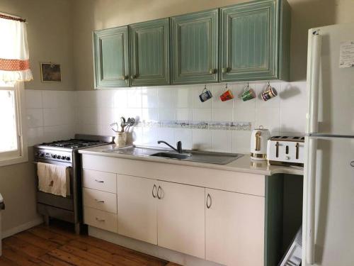 a kitchen with green cabinets and a sink and a refrigerator at Glenlyon Dam Holiday Cottage & Farmstay in Stanthorpe