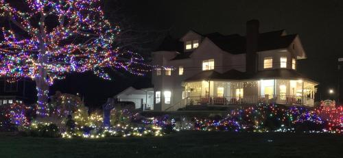 a christmas tree in front of a house with christmas lights at Anchorage Inn in Coupeville