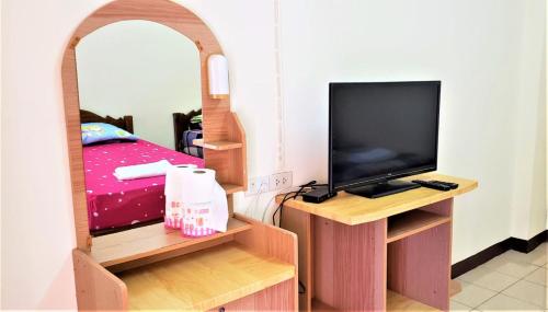 um quarto com uma cama, uma televisão e um espelho em Baan Yuyuen em Pathum Thani