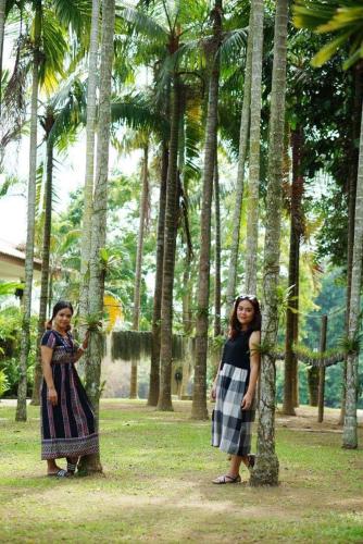 two young girls standing next to palm trees at Vimannam Resort in Phetchaburi