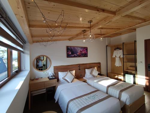 a bedroom with two beds and a desk and a mirror at Lasol Boutique Hotel in Da Lat