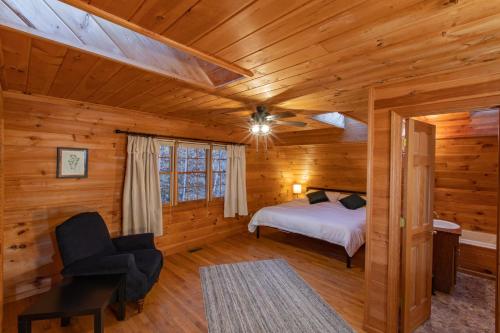 a bedroom in a log cabin with a bed and a chair at Treetops Cabin easy to Asheville with fast wifi and great view in Swiss