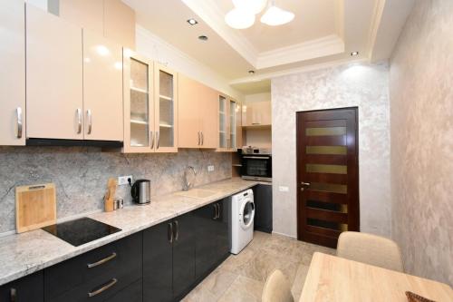 Malibu في يريفان: مطبخ مع خزائن بيضاء وغسالة ومجفف