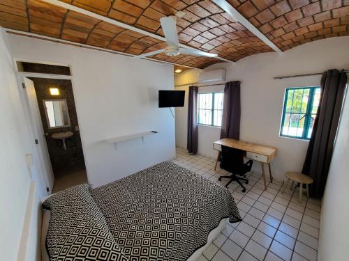 a bedroom with a bed and a desk in a room at Madre Cuixe Suites in Peñita de Jaltemba
