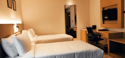 a hotel room with two beds and a desk at Sunhill Portico in Siliguri
