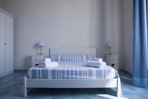 a bedroom with a white bed with blue and white stripes at Guarinelli 88 in Gaeta