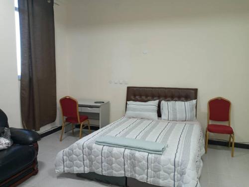 1 dormitorio con 1 cama con 2 sillas y escritorio en Betsi Bed & Breakfast (BBB) en Addis Abeba