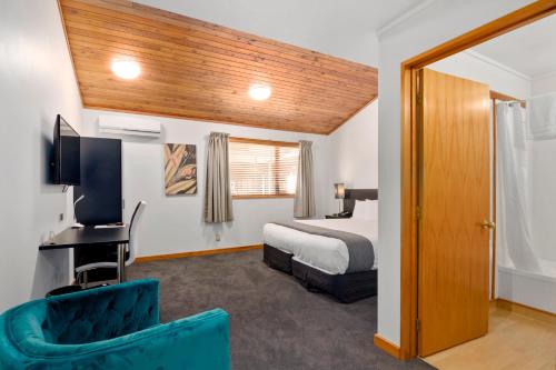 a bedroom with a bed and a desk with a television at Riverside Hotel Marlborough in Blenheim