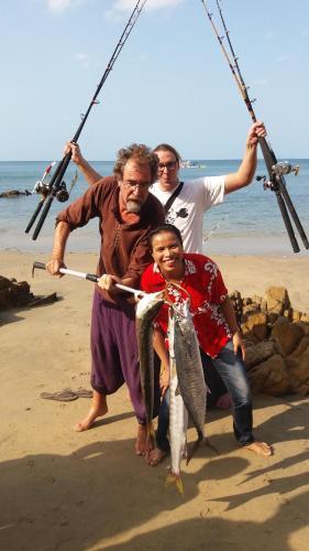 a group of three people holding fish on a fishing pole at Kohjum Seafront Resort in Ko Jum