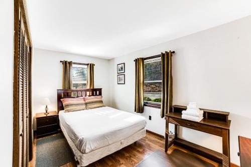 a bedroom with a bed and a desk and two windows at Antler Lake House in North Creek