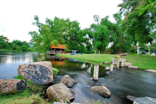 a river with rocks and a house in the background at Vimannam Resort in Phetchaburi