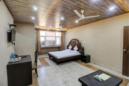 FabHotel Pinjore Holiday Home في Pinjaur: غرفة نوم بسرير ومروحة سقف