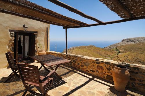 a table and chair on a balcony with a view of the ocean at Thalori Traditional Ecotourism Village in Kapetanianá