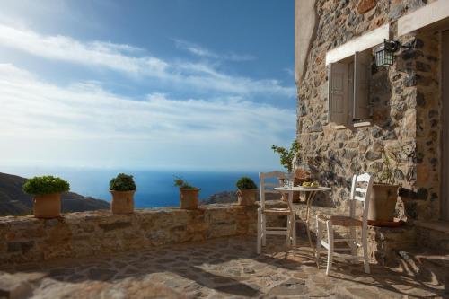 a patio with a table and chairs and a view of the ocean at Thalori Traditional Ecotourism Village in Kapetanianá