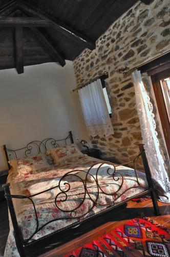 a bedroom with a bed in a stone wall at Thalori Traditional Ecotourism Village in Kapetanianá