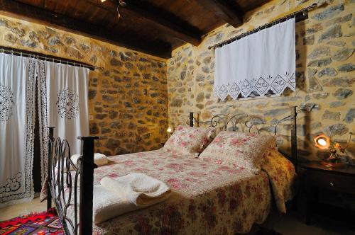 a bedroom with a bed in a stone wall at Thalori Traditional Ecotourism Village in Kapetanianá