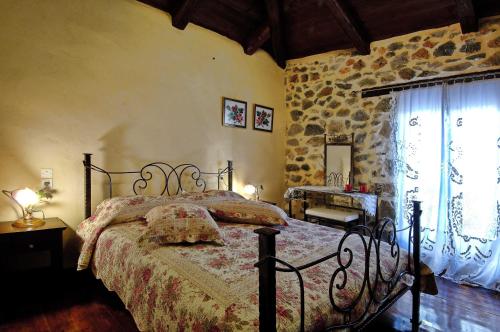 a bedroom with a bed and a stone wall at Thalori Traditional Ecotourism Village in Kapetanianá