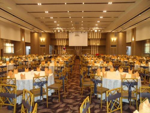 a banquet hall with tables and chairs and a screen at Hyunjin Tourist Hotel in Donghae