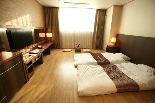 a hotel room with two beds and a television at Hyunjin Tourist Hotel in Donghae