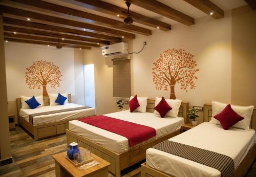 two beds in a room with trees on the wall at Hotel Ganesh Palace in Rāmeswaram
