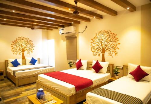 two beds in a room with two trees on the wall at Hotel Ganesh Palace in Rāmeswaram