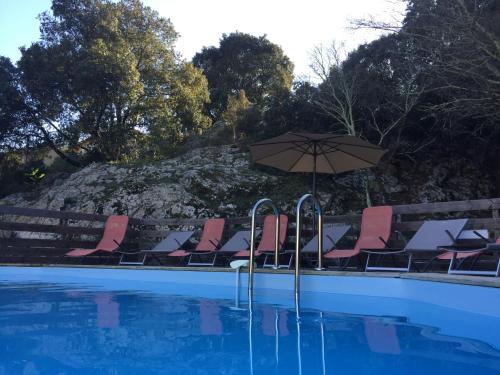 a group of chairs and an umbrella next to a swimming pool at L'EMPREINTE in Salavas