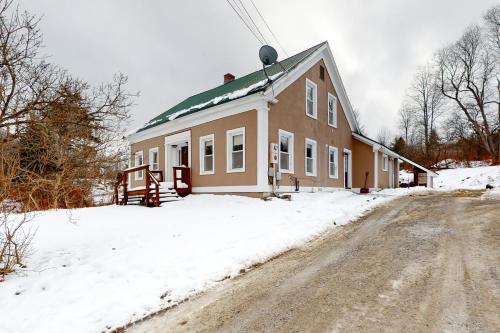 a house in the snow next to a dirt road at Mount Holly Ski House in Mount Holly