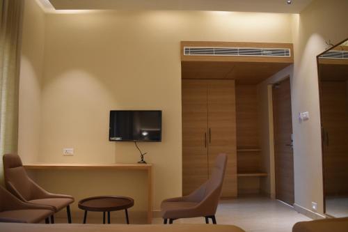 a room with chairs and a tv on the wall at Hotel VPS Grand in Palani
