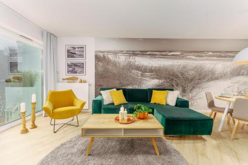 a living room with a green couch and a table at CHILLIapartamenty - Nadmorskie Tarasy - MORSKI z dostępem do basenu in Kołobrzeg