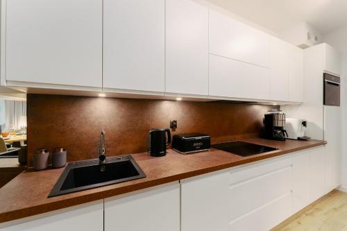 a kitchen with white cabinets and a sink at CHILLIapartamenty - Nadmorskie Tarasy - MORSKI z dostępem do basenu in Kołobrzeg