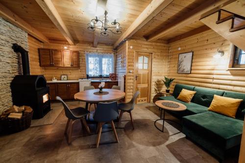 een woonkamer met een groene bank en een tafel bij Jurajskie Domki Pod Młyńską Skałą in Zdów