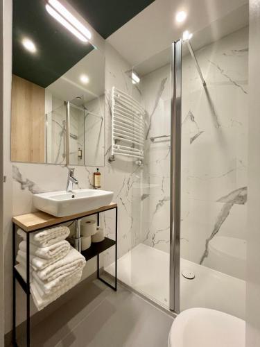 a white bathroom with a sink and a shower at Wilanów Residence Apartments in Warsaw