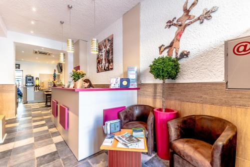 a lobby of a restaurant with two chairs and a counter at Hotel Le 21 in Saint-Raphaël