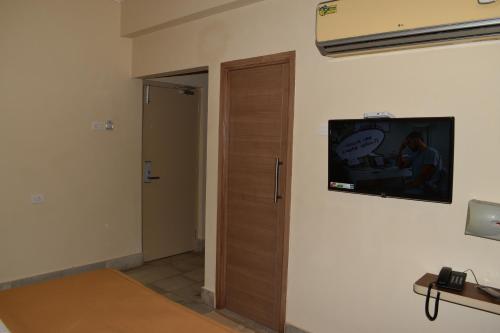 a room with a door with a television on the wall at Hotel VPS Grand in Palani