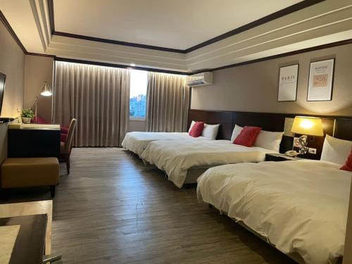 a hotel room with three beds and a window at Felicity Business Hotel in Taichung