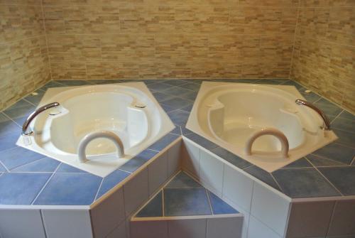 two tubs in a bathroom with blue tiles at Zwieseler Waldhaus in Lindberg