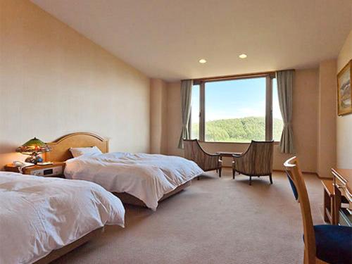 a bedroom with two beds and a desk and a window at Arcadia in Nagano