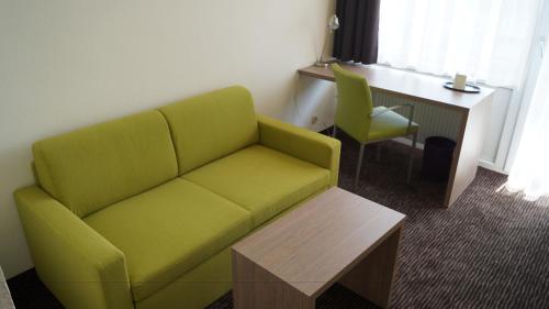 ein Wohnzimmer mit einem grünen Sofa und einem Schreibtisch in der Unterkunft Gästehaus Fernblick in Bad Wimpfen