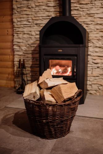 a basket of logs in front of a fireplace at Ranczo Czerwony Młyn in Zdów