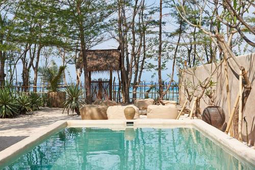 una piscina en un patio con árboles en The Island Houses Gili Meno, en Gili Meno