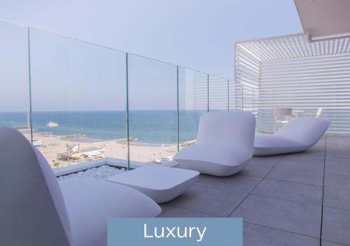 Cette chambre comprend des chaises blanches et offre une vue sur l'océan. dans l'établissement Hotel Alexandra - Beach Front -XXL Breakfast & Brunch until 12 30pm, à Misano Adriatico