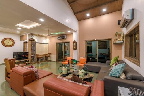 a living room with a couch and a glass table at SaffronStays Adora Woods & Hills, Luxury Pool Villa in Murud in Jambrung 