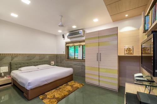 a bedroom with a bed and a television in it at SaffronStays Adora Woods & Hills, Luxury Pool Villa in Murud in Jambrung 