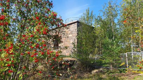 a brick building with red flowers and trees at Vanha-Merivartioasema in Kotka
